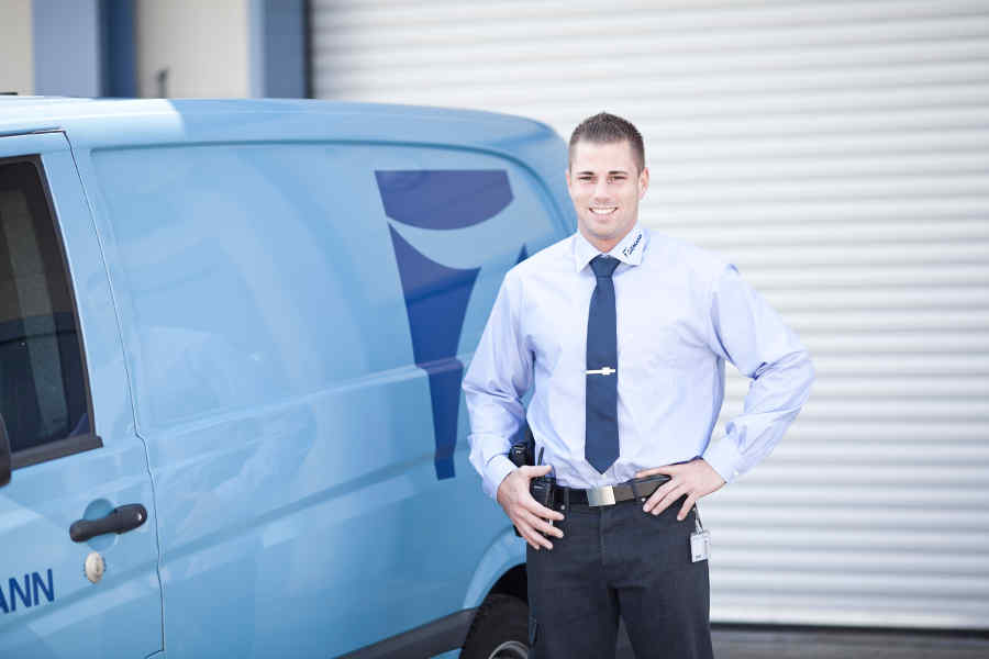 Ein Mann in einer Krawatte steht neben einem blauen Lieferwagen.