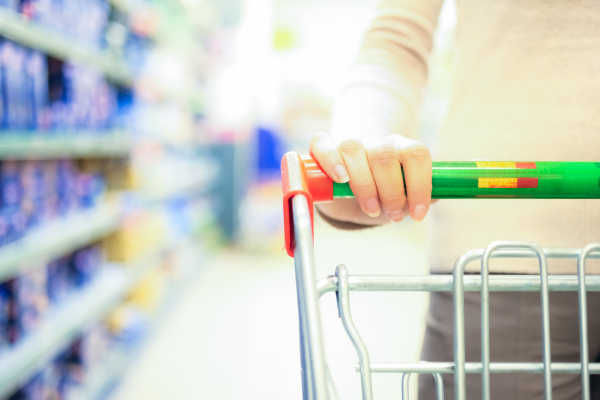 Eine Person schiebt einen Einkaufswagen in einem Supermarkt.